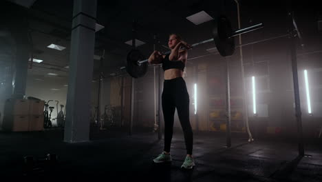 Female-bodybuilder-doing-exercise-with-weights-in-gym.-a-female-weightlifter-performs-a-barbell-lift-in-a-dark-gym.-Female-Bodybuilder-Does-Weight-Lift-Workout-Exercises-in-the-Hardcore-Training